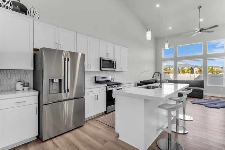 Kitchen featuring white cabinetry, stainless steel appliances, a center island with seating, and wood-finish flooring