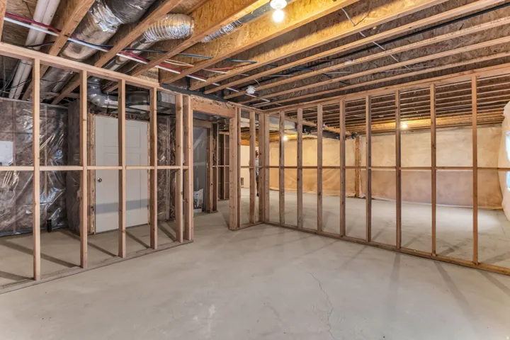 Unfinished basement with concrete flooring, exposed wood framing, and existing overhead ductwork