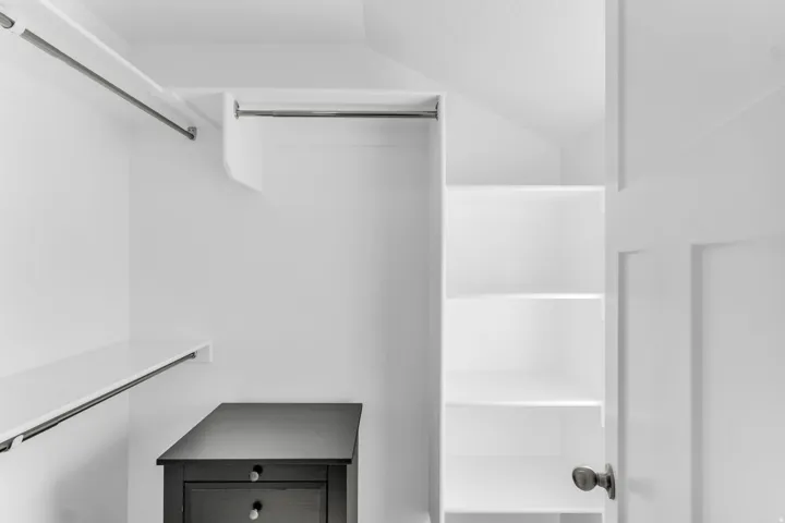 Walk-in closet with multiple hanging rods, built-in shelving, and a paneled door