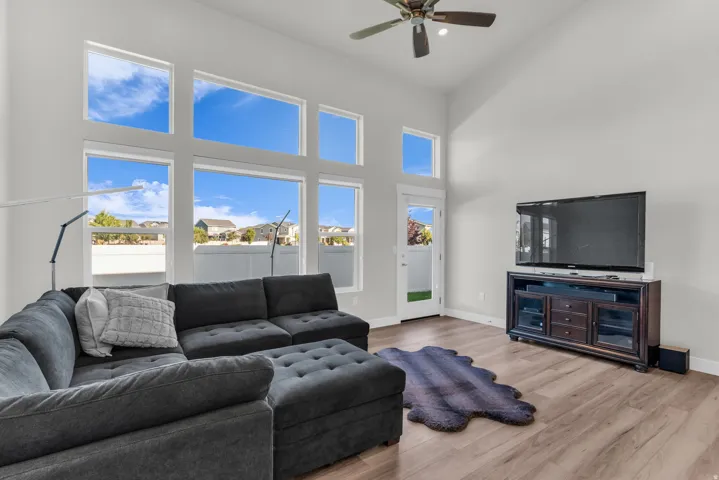 Expansive windows, wood-finish flooring, vaulted ceiling, built-in media console, and ceiling fan