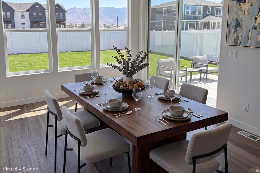 Sunroom! Multiple windows providing ample natural light, wood-finish flooring, sliding glass patio door, and a manicured lawn
