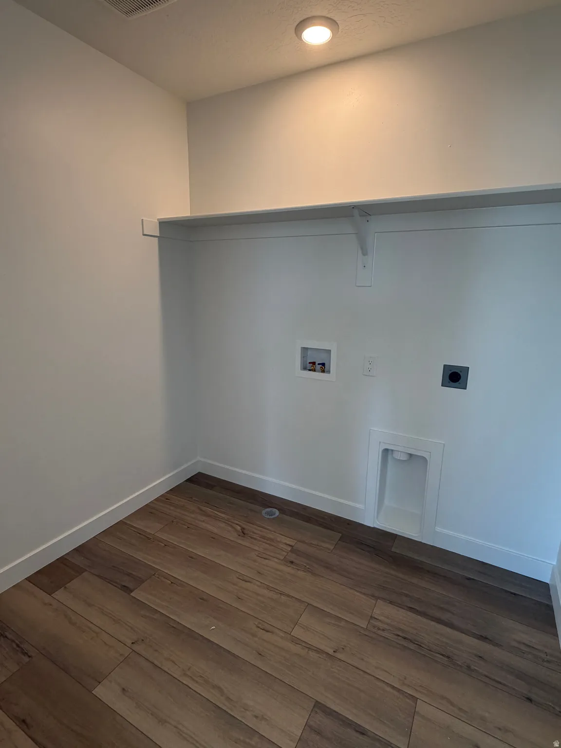 Laundry area with wood-finish flooring, white walls, built-in shelving, and recessed lighting