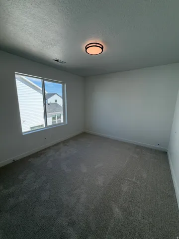 Carpeted room with a flush-mount ceiling light and a multi-pane window