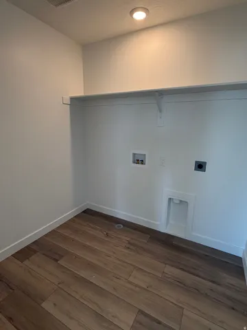 Laundry area with wood-finish flooring, white walls, built-in shelving, and recessed lighting