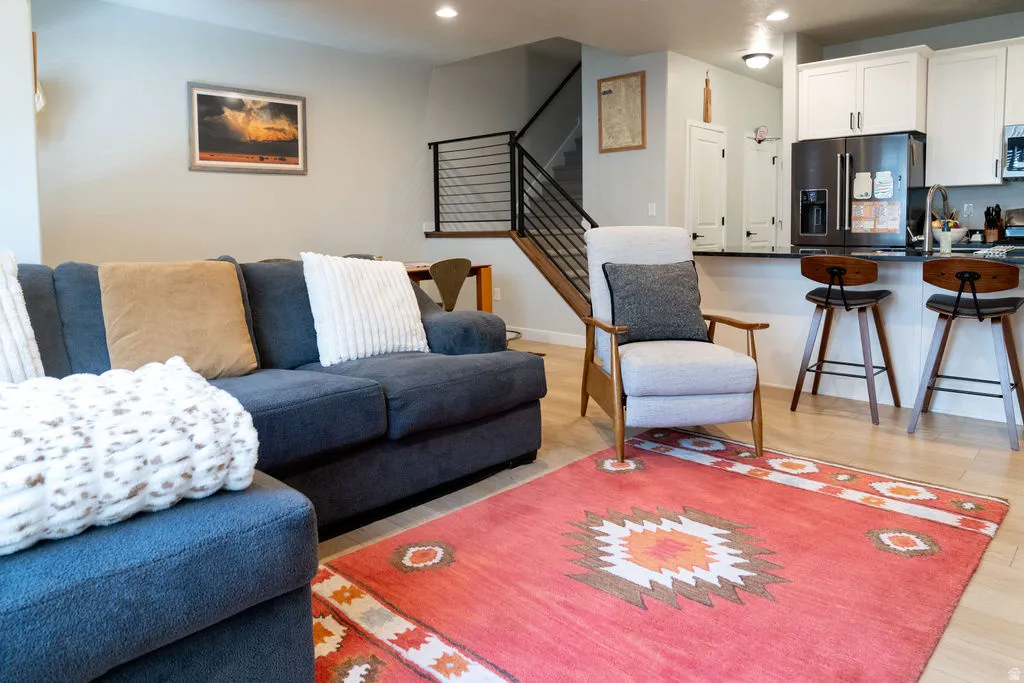 Open-concept living area with wood-finish flooring, recessed lighting, and a modern staircase with metal railings