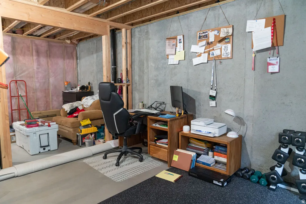 Unfinished basement space featuring exposed wood framing, concrete walls, and insulated wall sections