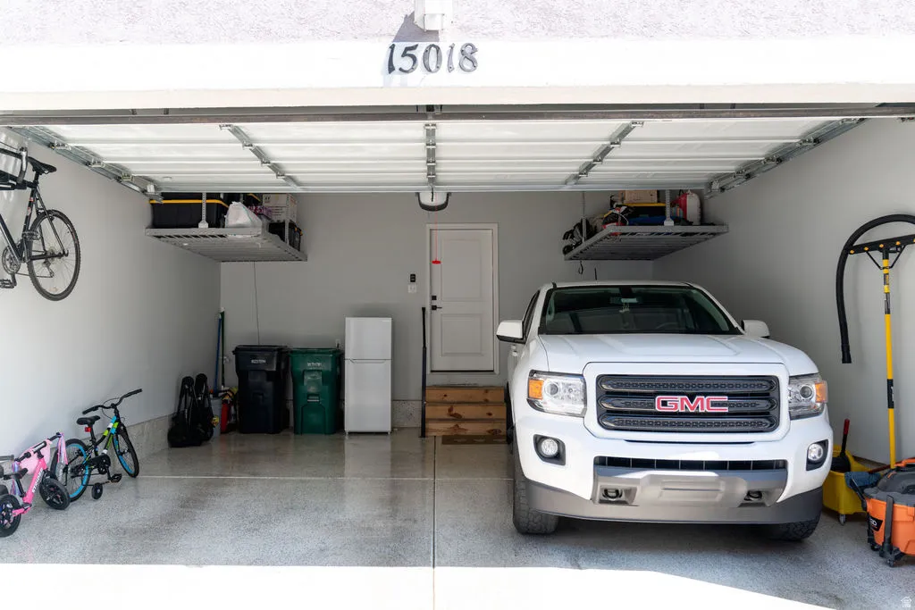 Two-car garage featuring overhead storage racks, an epoxy-coated floor, and a white entry door