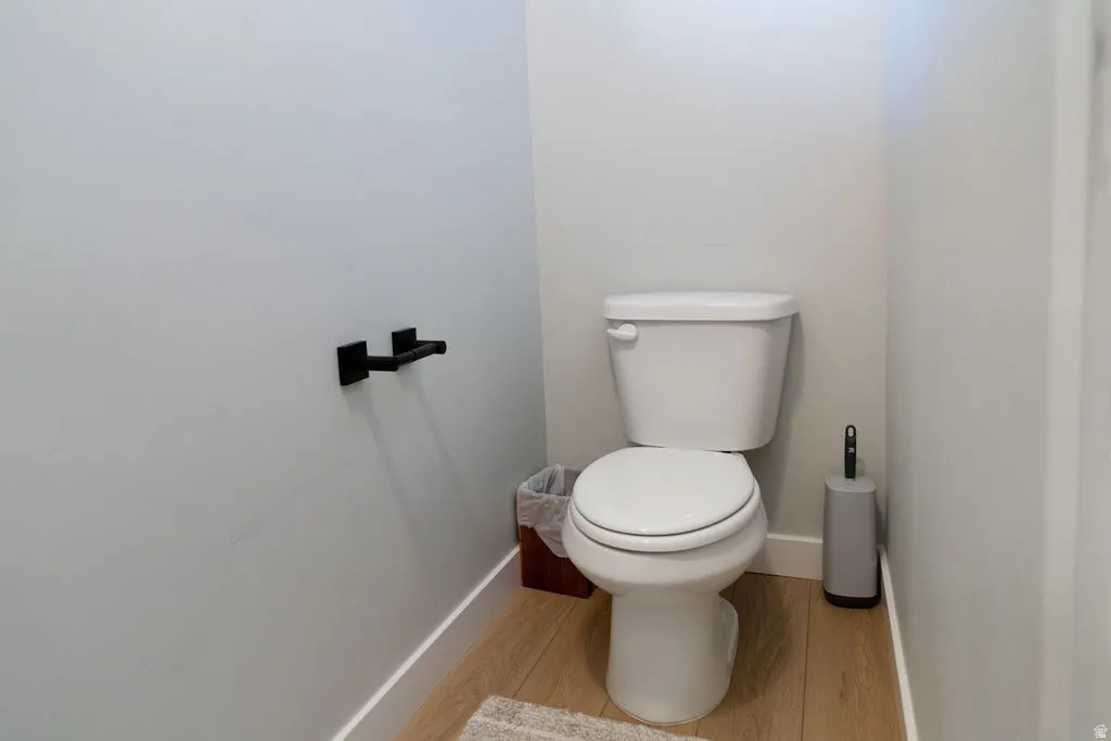 White toilet with matte black hardware and wood-finish flooring