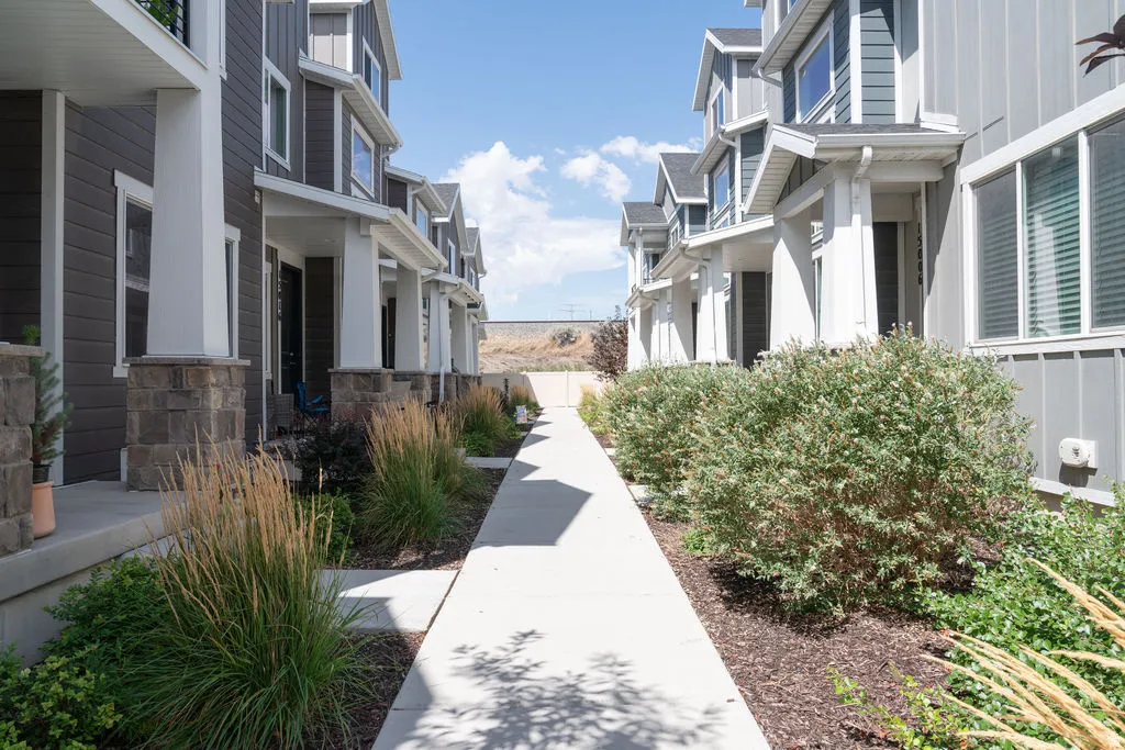 Modern townhome exteriors featuring dark siding, white trim, stone accents, and covered entryways