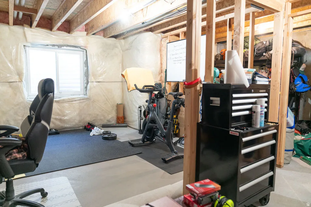 Unfinished basement with exposed wood framing, concrete flooring, and a large window