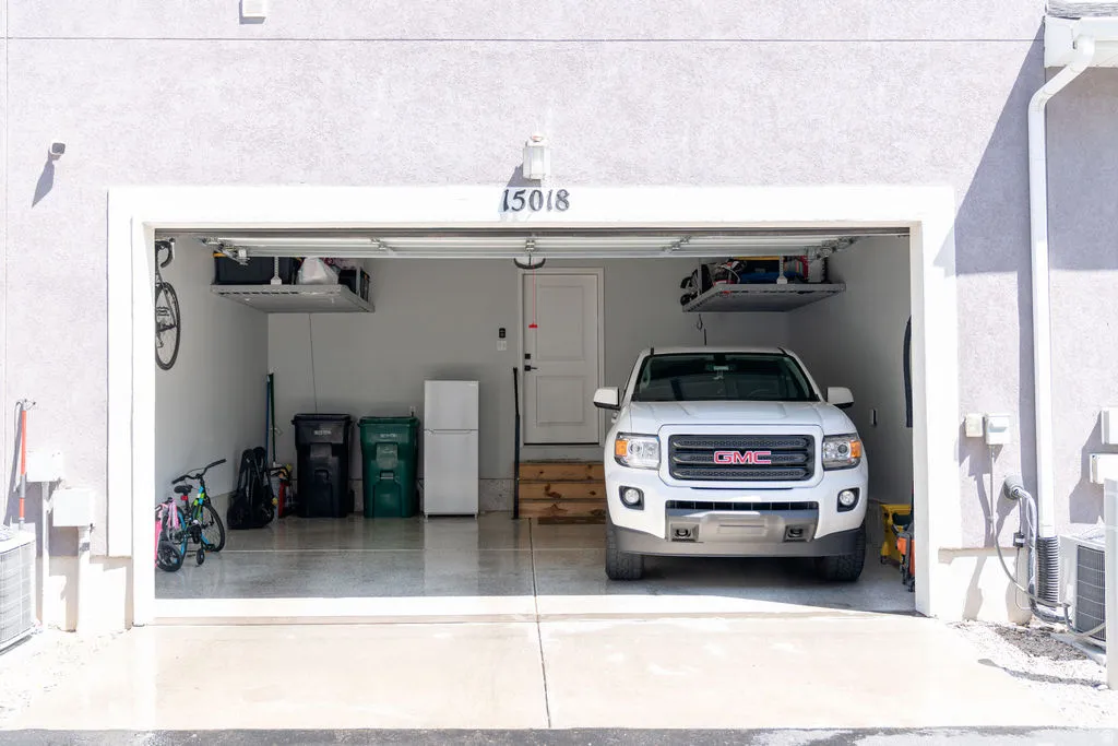 Attached garage with a roll-up door, an epoxy-coated floor, built-in overhead storage shelves, and a side access door