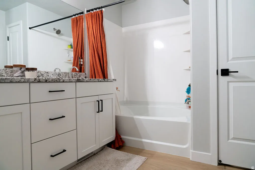 White vanity with a speckled countertop, dual under-mount sinks, and matte black hardware