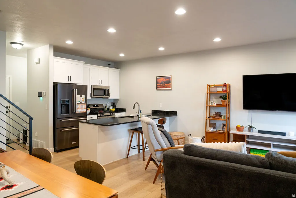 Integrated kitchen with white cabinetry and stainless steel appliances