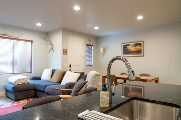 Kitchen island with a stainless steel undermount sink, gooseneck pull-down faucet, and dark stone countertop
