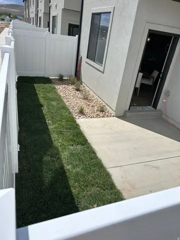 Private outdoor space featuring a concrete patio, landscaped rock bed, and a strip of lawn