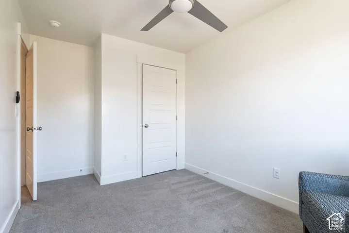 Neutral paint finishes, gray carpeting, modern ceiling fan, and white trim