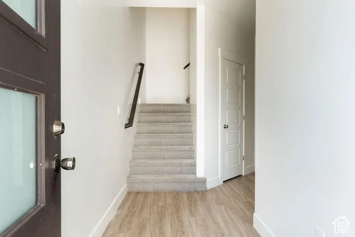 Entryway featuring a dark wood door with frosted glass, wood-finish flooring, a carpeted staircase with a dark handrail, and white paneled interior doors