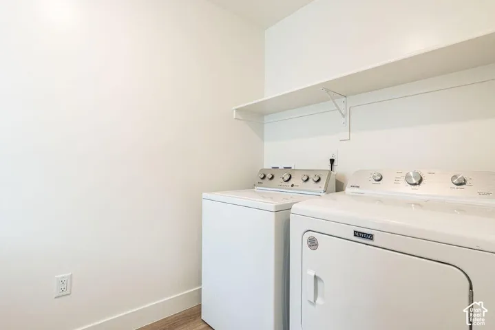 Laundry area featuring a built-in shelf, wood-finish flooring, and light-toned walls