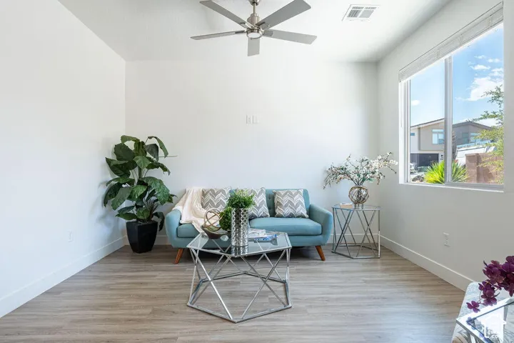 Bright interior space featuring wood-finish flooring, a large window, high ceilings, and a ceiling fan