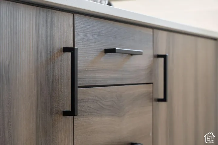 Wood-finish cabinetry with matte black hardware and a light-toned countertop