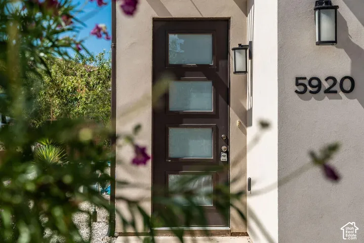 Contemporary entry door with frosted glass panels, two wall-mounted exterior light fixtures, and modern house numbers