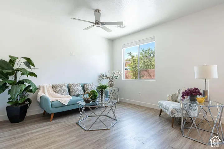 Recessed window with white trim, wood-finish flooring, ceiling fan, and white walls
