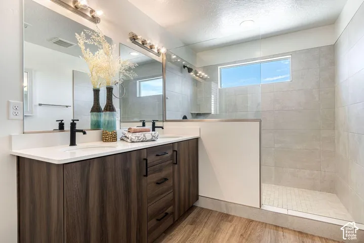 Spa-inspired primary bathroom featuring a dark wood-finish vanity with dual sinks, white quartz countertop, and polished chrome fixtures