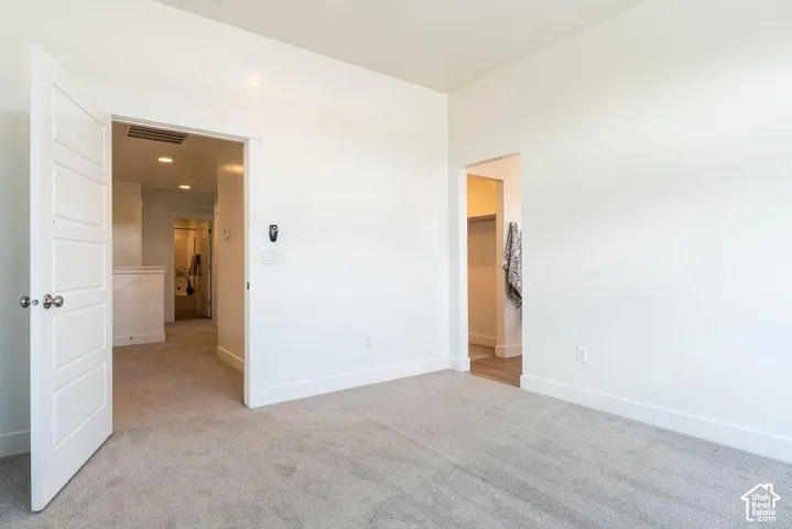 Spacious bedroom with neutral wall finishes, recessed ceiling lighting, and direct access to an ensuite bathroom