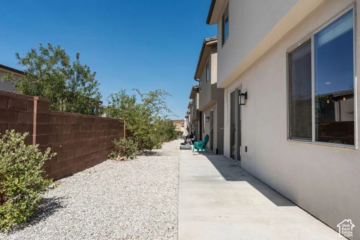 Stucco exterior with sliding glass doors, exterior wall sconces, and a concrete patio