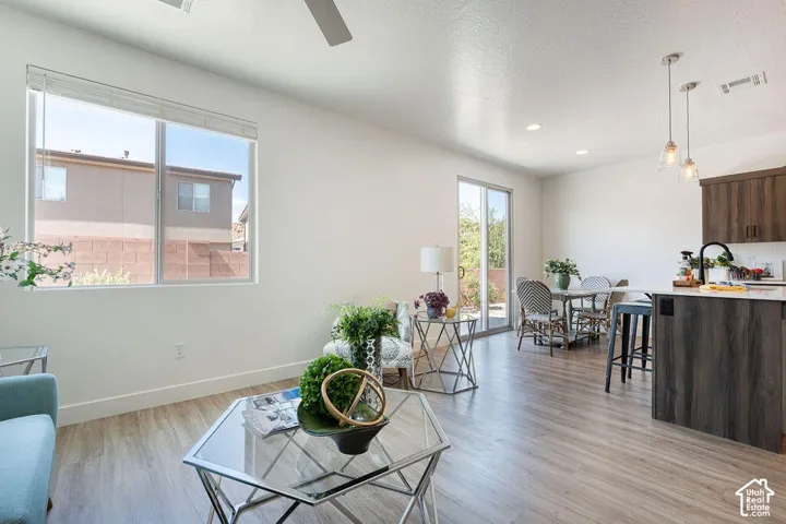 Open-concept living space with wood-finish flooring throughout, featuring a modern kitchen with dark cabinetry and stainless steel appliances, pendant lighting, and dining area