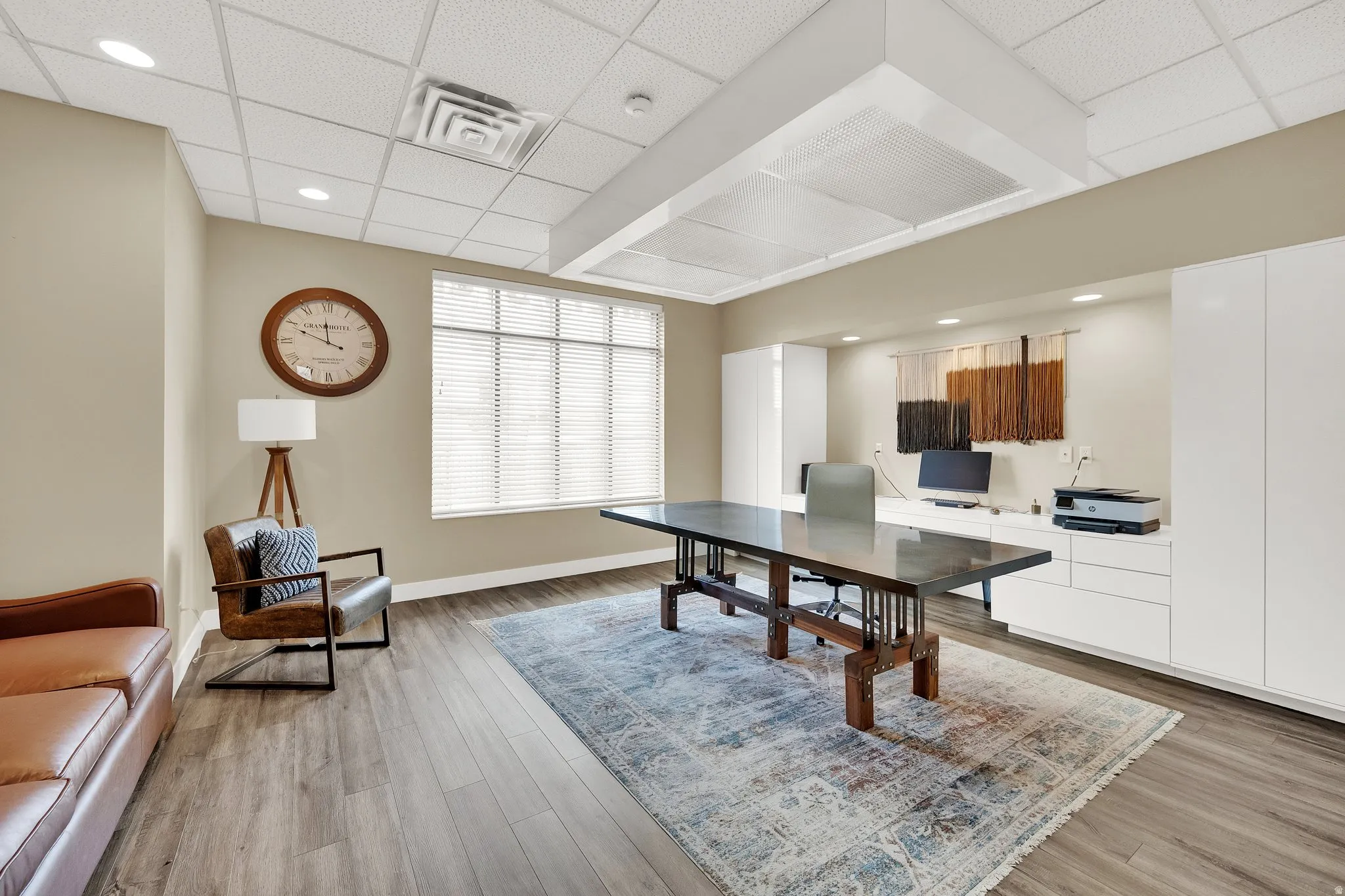 Wood-finish flooring throughout, large window with blinds, recessed lighting, drop ceiling, and built-in cabinetry
