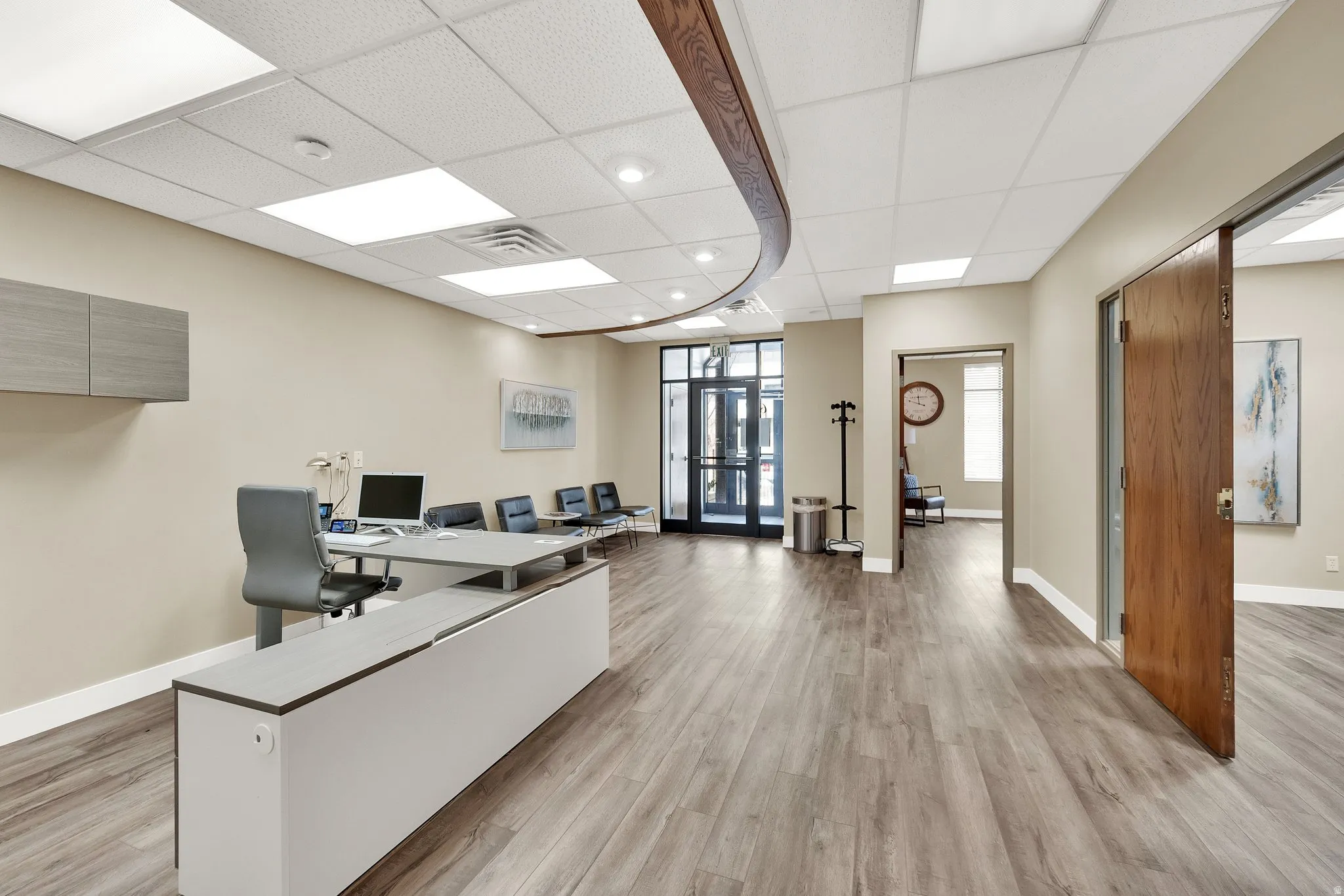 Spacious reception area featuring wood-finish flooring, recessed lighting, and a front entry with glass doors