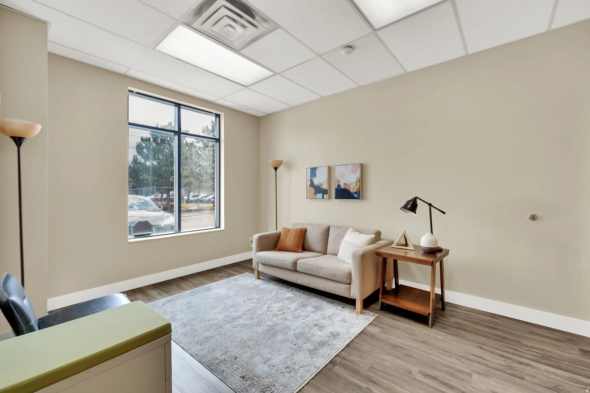 Recessed lighting with a drop ceiling, wood-finish flooring, and large window