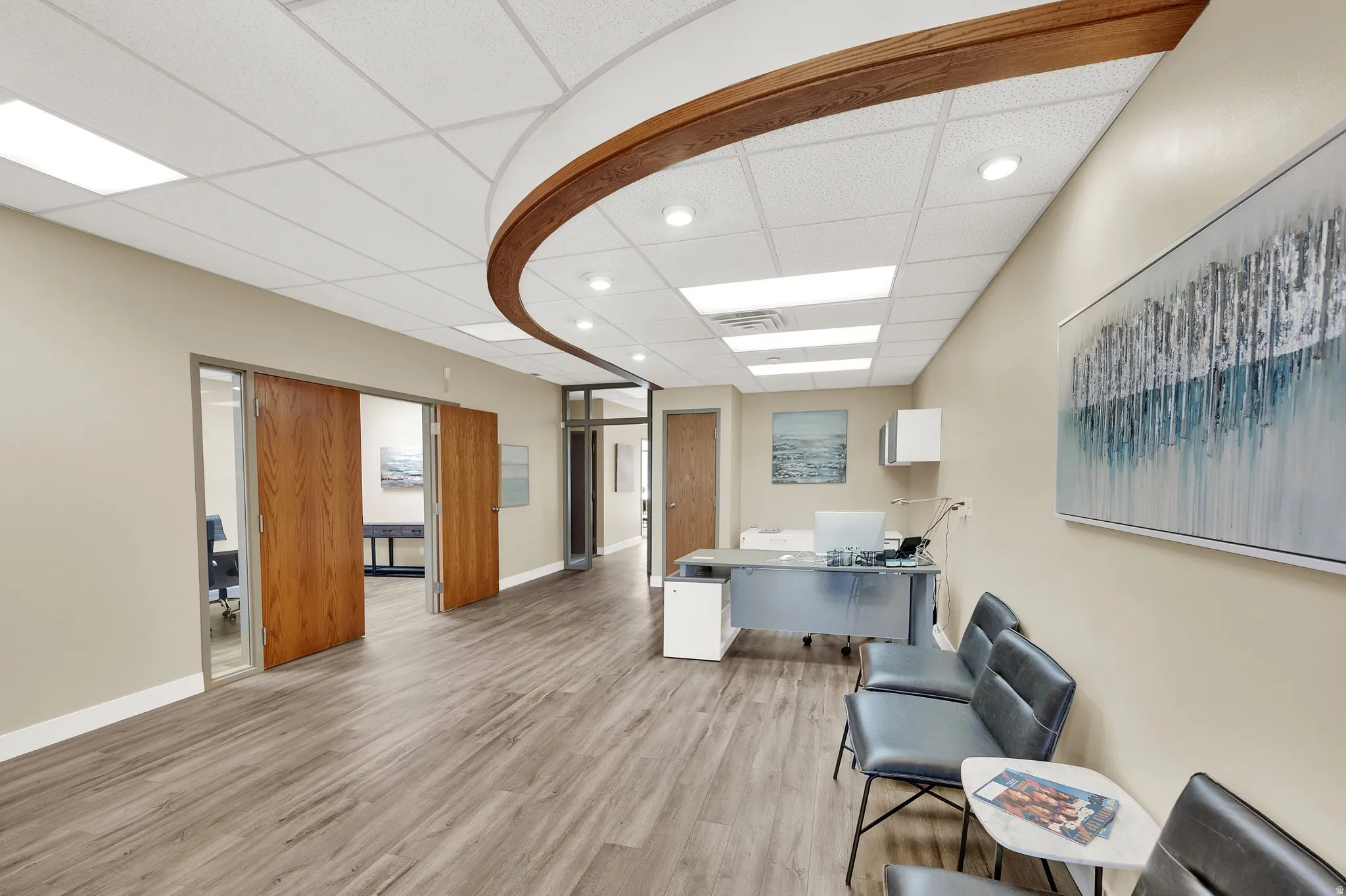 Wood-finish flooring throughout, drop ceiling with recessed lighting, integrated wood-finish ceiling accent, and multiple glass-paneled entryways