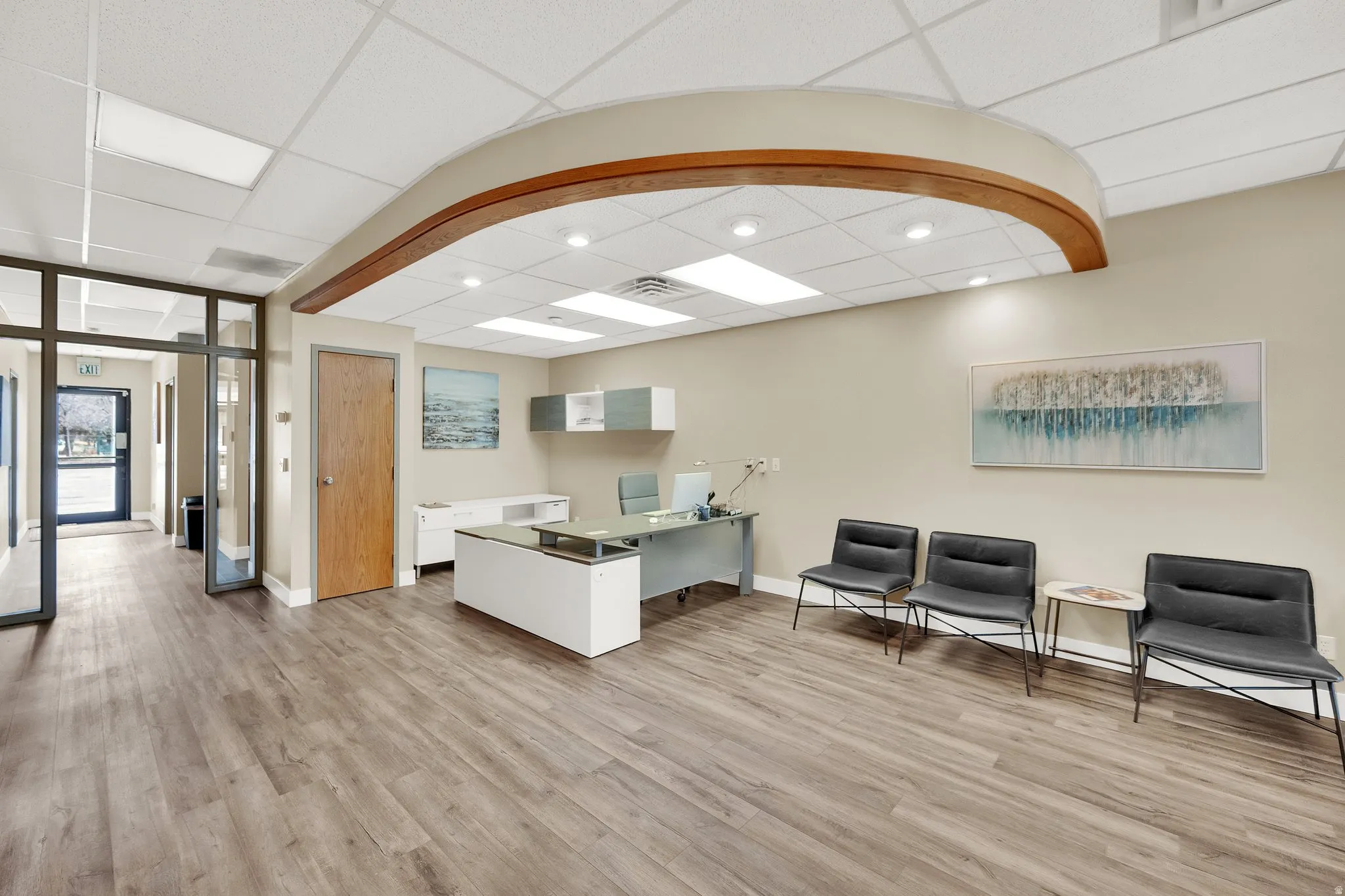 Wood-finish flooring, recessed lighting, drop ceiling, and wood-paneled door