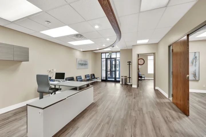 Spacious reception area featuring wood-finish flooring, recessed lighting, and a front entry with glass doors