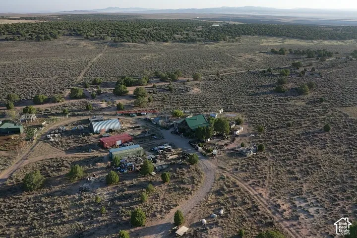 Expansive land parcel featuring multiple structures, including a primary residence with a green roof, several outbuildings, and a network of unpaved access roads