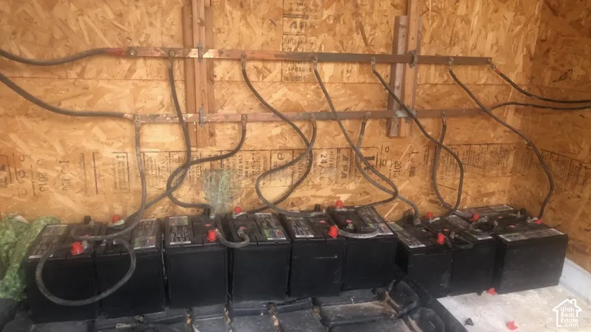 Battery storage system with copper grounding bus bars and organized electrical cabling mounted to plywood wall panels
