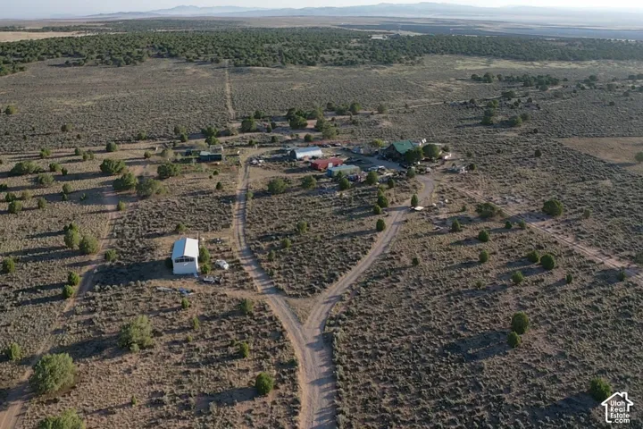 Expansive property featuring multiple structures, natural landscaping, and a dirt road network