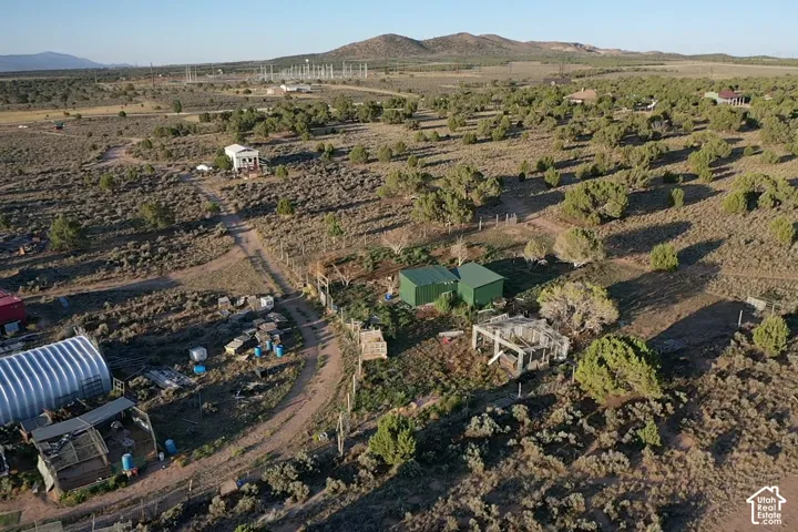 Expansive property featuring multiple structures, including two green metal outbuildings, a white residence, and a large quonset hut