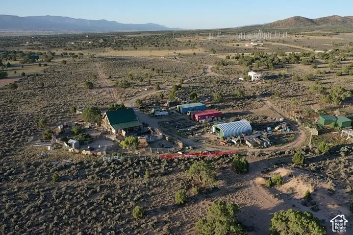 Rural property featuring a main structure with a green metal roof, multiple outbuildings, and a large quonset hut