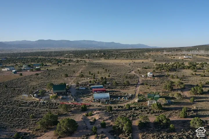 Expansive land parcel with multiple structures, natural desert landscaping, and distant mountain ranges