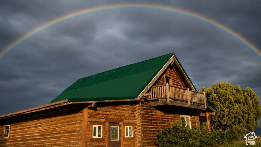 Log home featuring a green metal roof, a second-story balcony with wood railing, and multiple windows