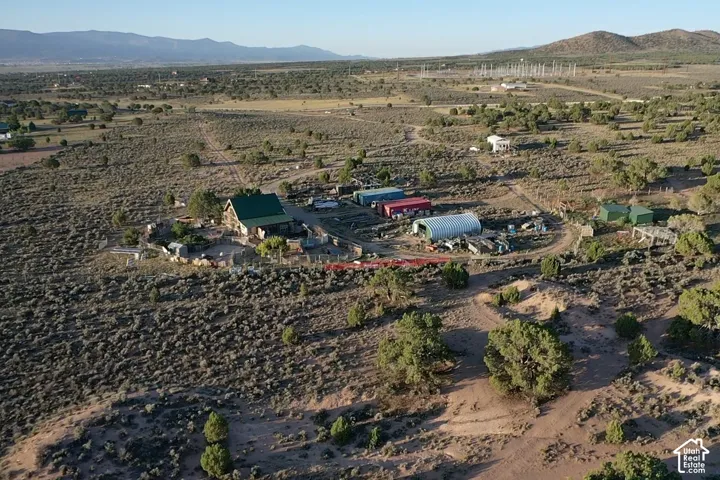 Expansive rural property featuring a main structure with a green roof, multiple outbuildings including a Quonset hut, and a large cleared area