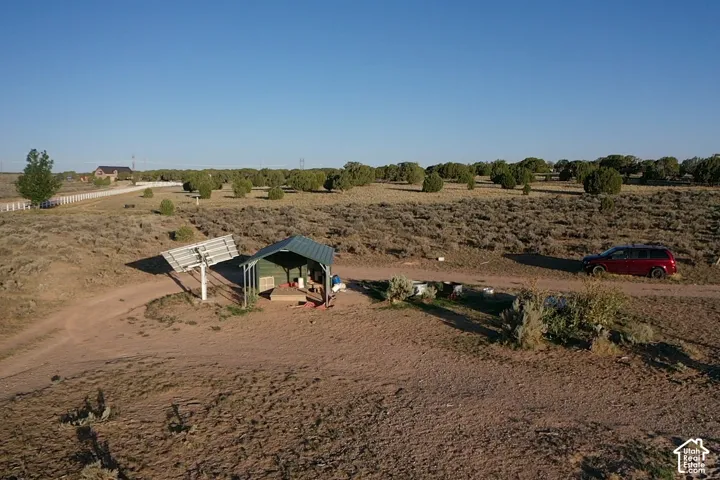 Solar panel array with a metal-roofed shelter on a dirt lot
