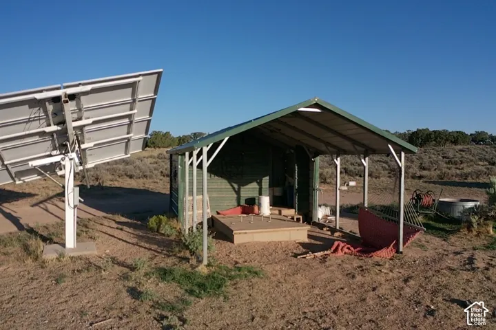 Solar panel array with a metal support structure, adjacent to a green shed with an attached carport