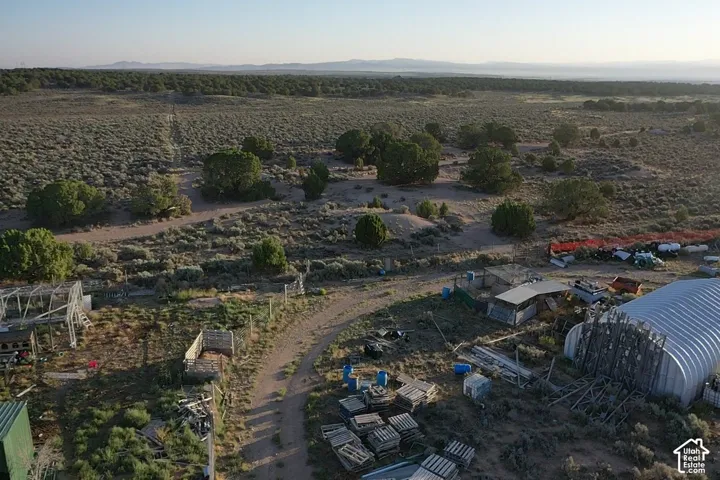 Extensive rural property featuring a large quonset hut, various outbuildings, and natural shrubland