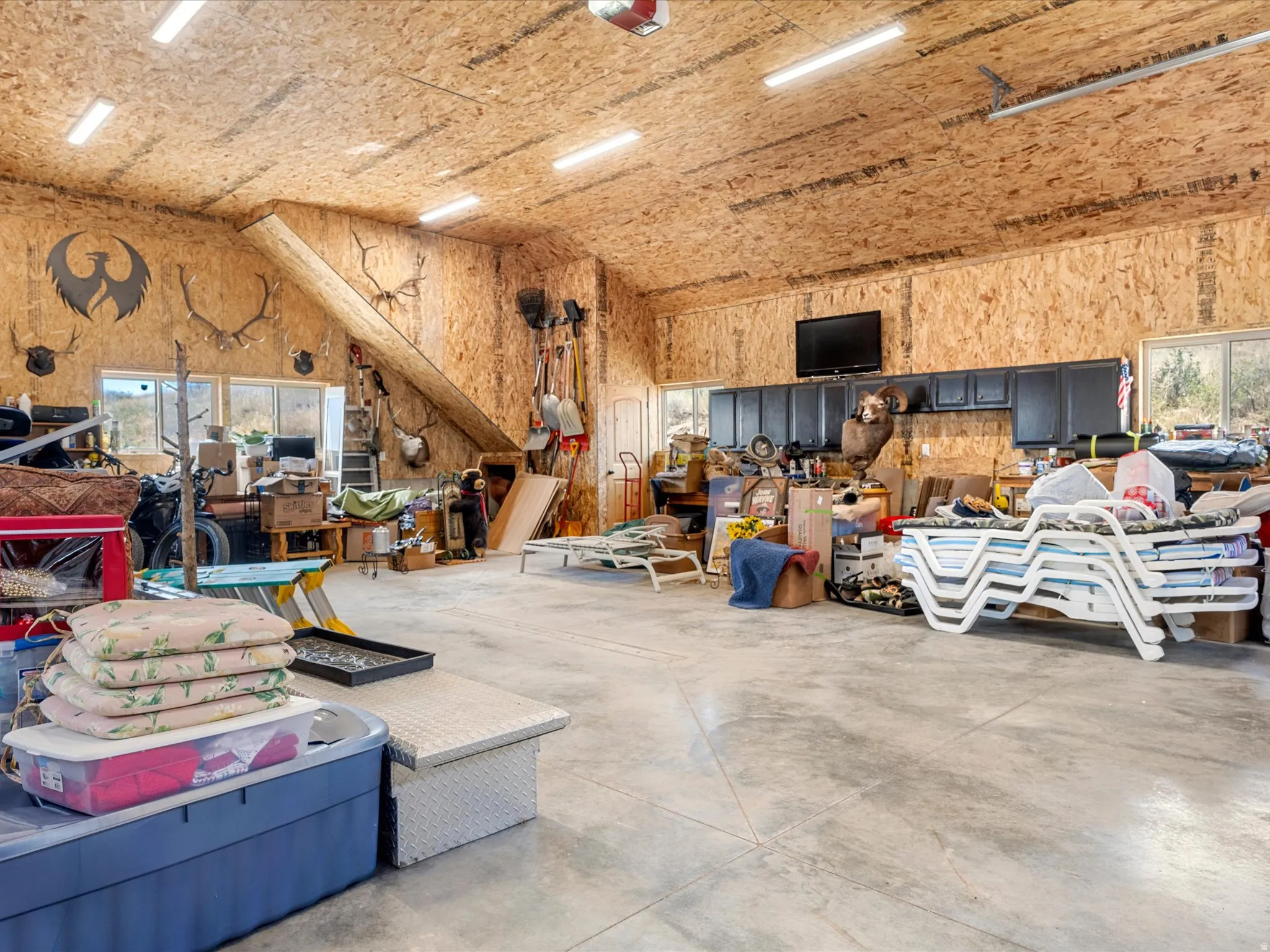 Spacious interior with exposed wood-finish paneling, concrete flooring, and multiple windows