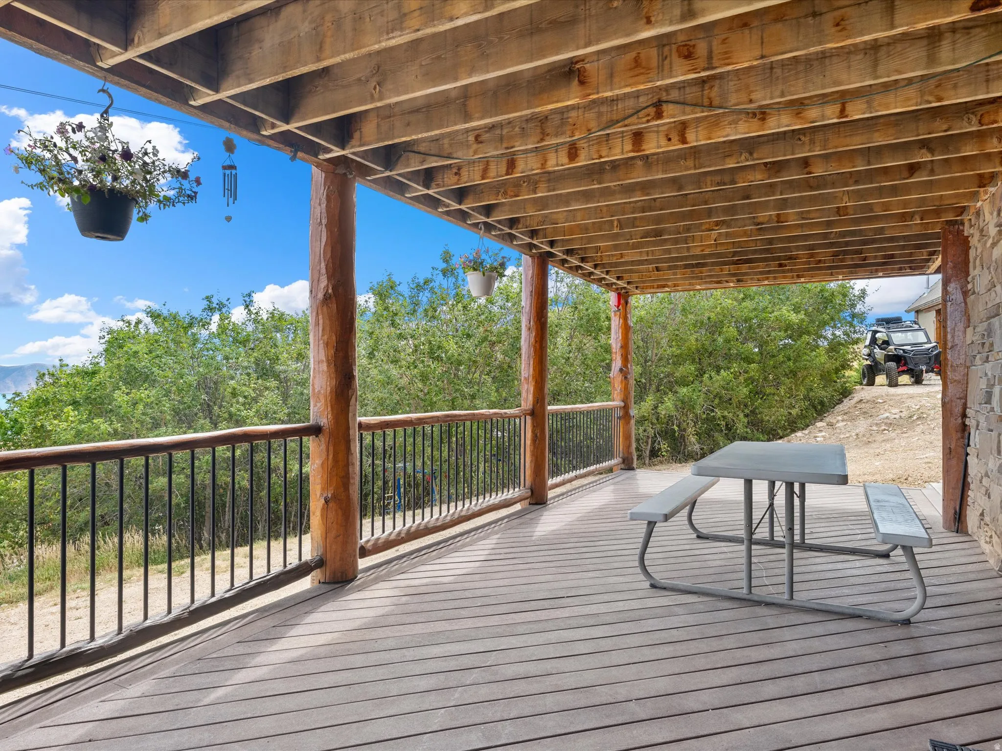 Expansive outdoor deck featuring wood-finish flooring, natural wood support columns, and black metal railings