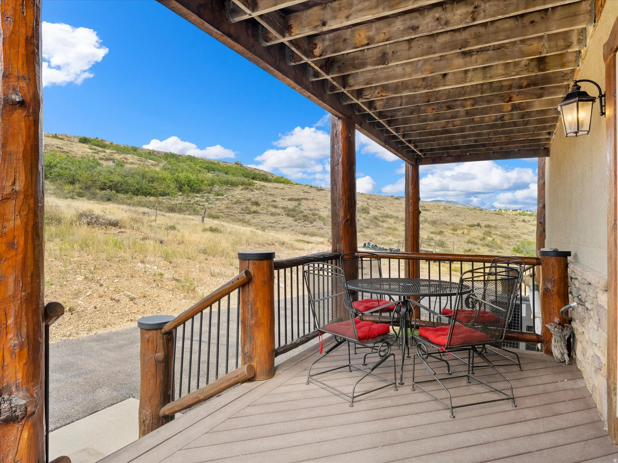 Covered outdoor deck with wood-finish flooring, log pillars, and a metal balustrade